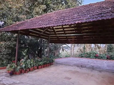 a wooden pavilion with plants in a garden at Sardar Bahadur's Heritage Bungalow Estate Stay in Napoklu