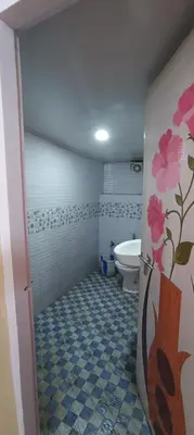a bathroom with a toilet and a sink and a bathroom door at Honeybee Homestay by The Jungle Stay Groups in Vālpārai