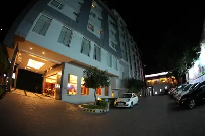 a white car parked in a parking lot next to a building at RATHNA RESIDENCY in Coimbatore