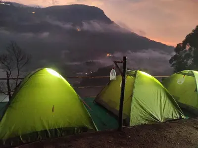 two green tents with a mountain in the background at Misty Mountains Holiday Homes in Vattavada