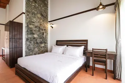 a bedroom with a bed and a desk in a room at Havon Plantation Resorts in Varagampadi