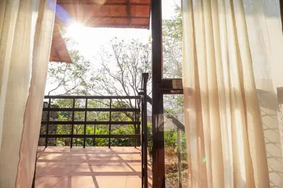a view of a balcony from a window with curtains at Havon Plantation Resorts in Varagampadi