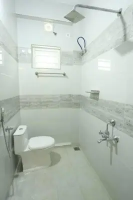 a white bathroom with a toilet and a shower at Yelza Hotel and Residence in Alwaye