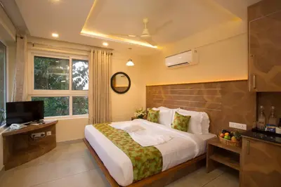 a bedroom with a large bed and a television at Amrezy Resort and Spa by Stride, Wayanad in Vythiri