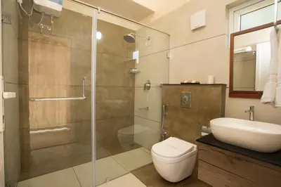 a bathroom with a shower and a toilet and a sink at Amrezy Resort and Spa by Stride, Wayanad in Vythiri