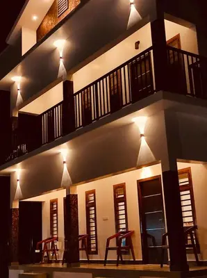 a building with tables and chairs in front of it at night at The Lavender Resort Waynad in Vaduvanchal