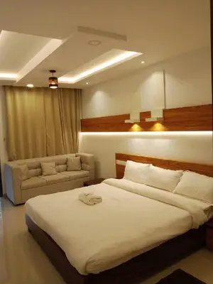 a bedroom with a large white bed and a couch at The Lavender Resort Waynad in Vaduvanchal