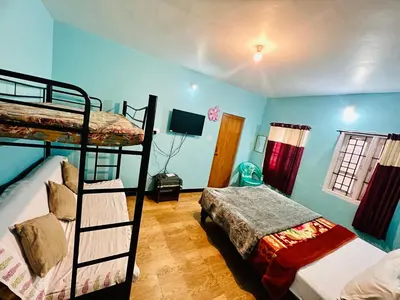 a bedroom with two bunk beds and a television at Down House 19 Ooty - TEYT HOLIDAYS in Ooty