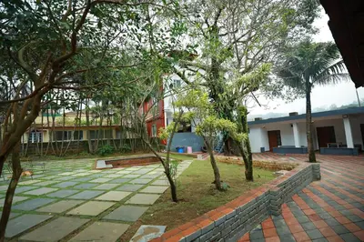 a courtyard with trees in front of a building at Ayla Homes in Madikeri