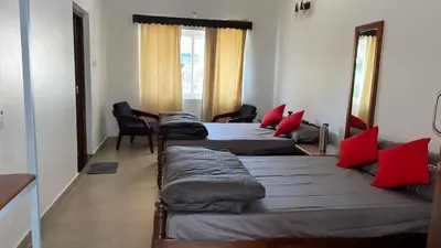 three beds in a room with red pillows on them at Ayla Homes in Madikeri