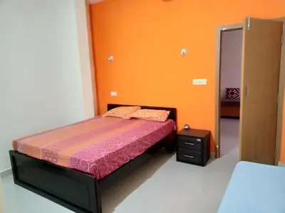a bedroom with a bed and an orange wall at Krishna Kuteera in Siddapur