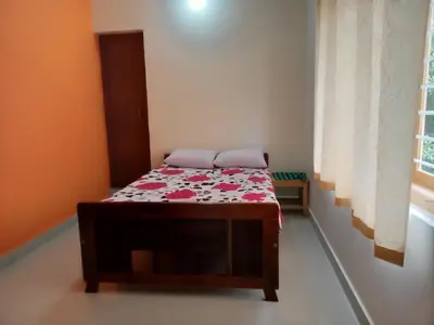 a small bedroom with a bed with a floral comforter at Krishna Kuteera in Siddapur