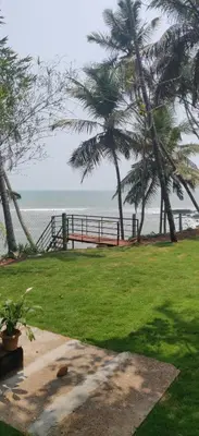 a park with two palm trees and the ocean at Perch by the sea in Kannur
