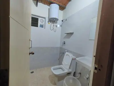 a white bathroom with a toilet and a sink at Minimal Poshtel in Mysore