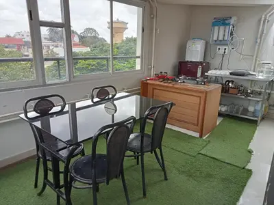 a table and chairs in a room with a kitchen at Minimal Poshtel in Mysore