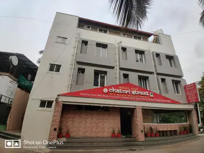 a tall white building with a red sign on it at Minimal Poshtel in Mysore
