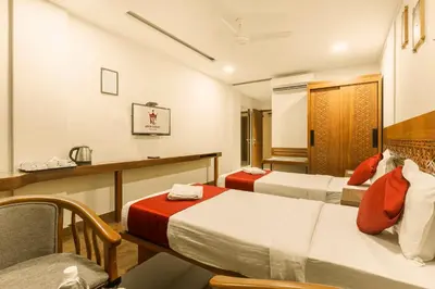 a hotel room with two beds and a chair at KINGS CALICUT in Kozhikode