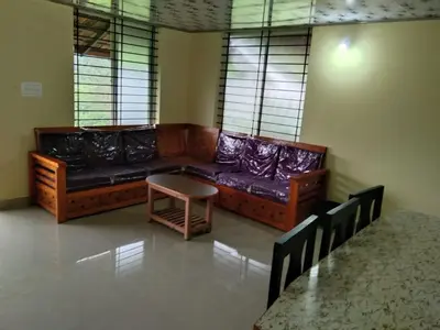 a living room with a couch and a table at SAMZ ESTATE Stay 3BHK in Madikeri