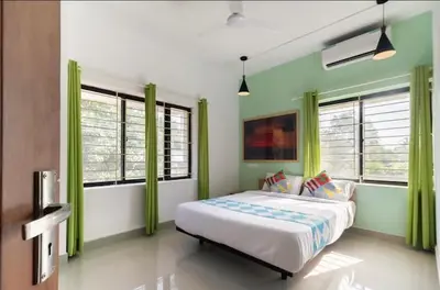 a bedroom with a large bed with green curtains at Ecoville suites in Kozhikode