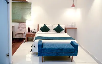 a bedroom with a bed and a blue chair at Harivaram Yuga in Guruvāyūr