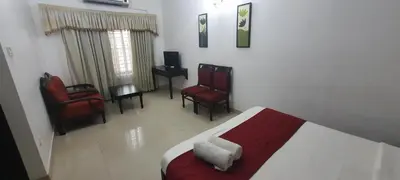 a bedroom with a bed and chairs in a room at Gee Bee Palace in Angamali