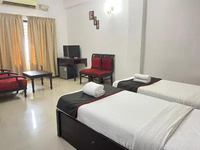 a hotel room with two beds and a desk and chairs at Gee Bee Palace in Angamali