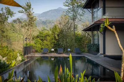 a house with a swimming pool and mountains in the background at Flora Vythiri Resort Wayanad in Vythiri