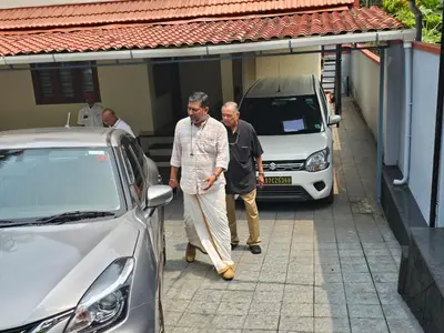 two men walking down a street next to a car at Saaketh Holiday Home in Kozhikode