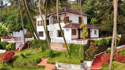 a house on a hill with palm trees at Willo Stays On the beach Sea view Ocean Hues holiday home in Kannur