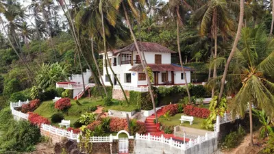 a house on a hill with palm trees at Willo Stays On the beach Sea view Ocean Hues holiday home in Kannur