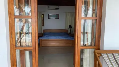 a small bedroom with a bed and two glass doors at Willo Stays On the beach Sea view Ocean Hues holiday home in Kannur