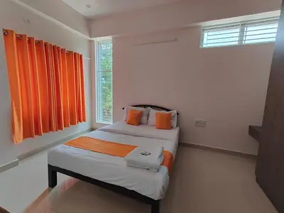 a bedroom with two beds with orange curtains at Meer Stay - Premium Service Apartments in Vānivilāsa Puram