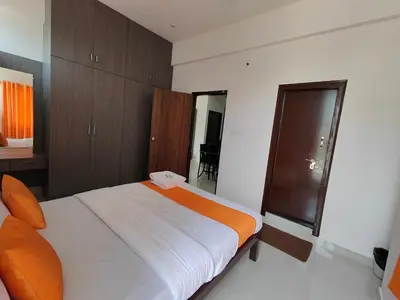 a bedroom with a large white bed and wooden cabinets at Meer Stay - Premium Service Apartments in Vānivilāsa Puram