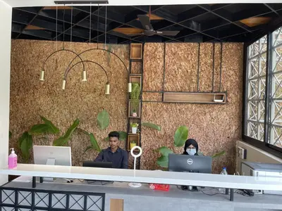 two people sitting at a desk with their computers at Miracle Hotel and Resorts in Kozhikode