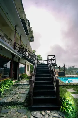 a stairway leading up to a building with a pool at Wild Elephant Resort in Kallar Vattiyar