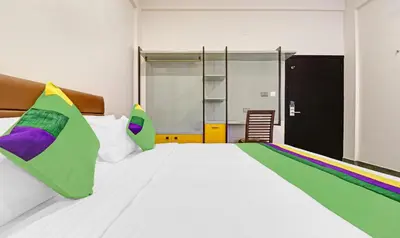 a bedroom with a large white bed with colorful pillows at Treebo Grand Vistara Airport Suites in Cochin