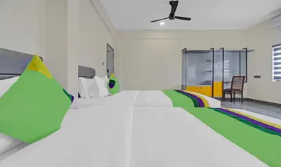 a bedroom with a large white bed with colorful pillows at Treebo Grand Vistara Airport Suites in Cochin