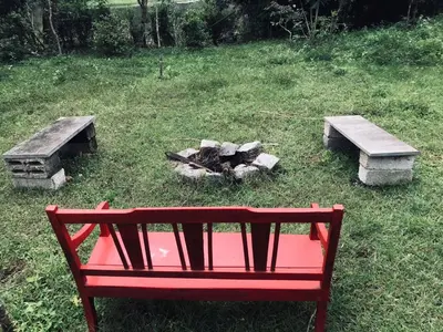 a red bench and two benches and a fire pit at Greenhouse Homestay in Siddapur