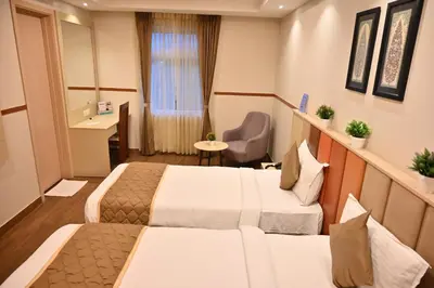 a hotel room with two beds and a desk at Soho Boutique Hotel in Mysore