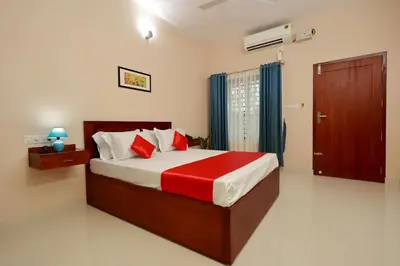 a bedroom with a large bed with red pillows at Isha Residency in Alwaye