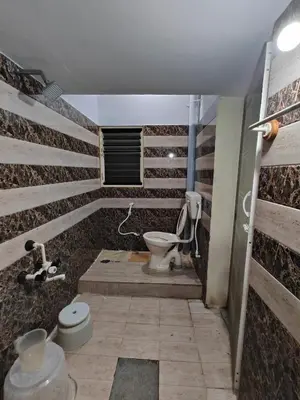 a bathroom with a toilet in a room with wooden walls at Yellow House in Mysore