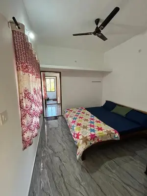 a bedroom with a bed and a ceiling fan at Shivalaya Homestay, Madikeri in Siddapur
