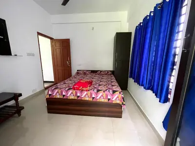 a bedroom with a bed in a room with blue curtains at Dakshinakasi Guest House in Thirunelli