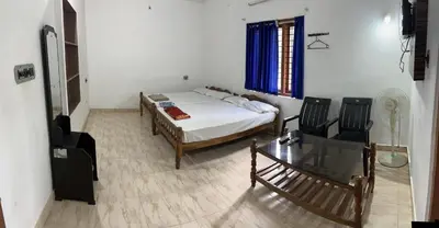 a bedroom with a bed and a table and chairs at Dakshinakasi Guest House in Thirunelli