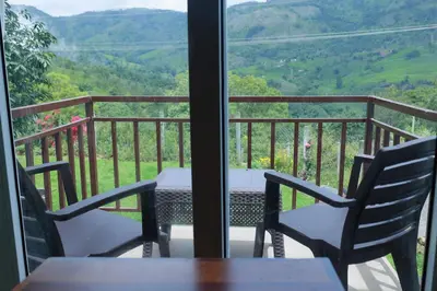 a table and chairs on a balcony with a view at Biosphere in Coonoor