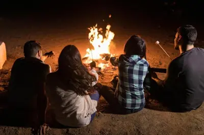 a group of people sitting around a fire at RAIN DROPS PREMIUM VILLAS - Athirappilly in Athirappilly