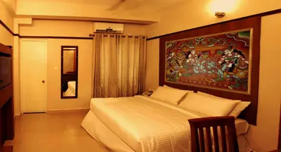 a bedroom with a large bed with a painting on the wall at Srivar Hotels in Guruvāyūr