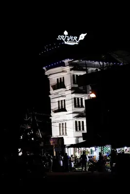 a white building with a clock on it at night at Srivar Hotels in Guruvāyūr