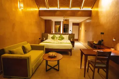 a bedroom with a bed and a couch and a table at Klov Resort & Spa in Wayanad
