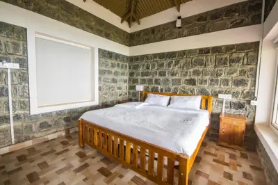 a bedroom with a bed and a stone wall at Tranqville Resorts in Ooty